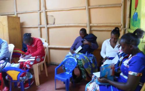 During a group meeting at the church, caregivers take notes as a Survival Specialist gives a presentation on an early childhood development topic.